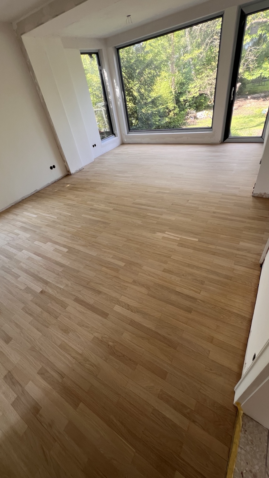 Aufbereiteter Stabparkettboden vor großen Fenstern