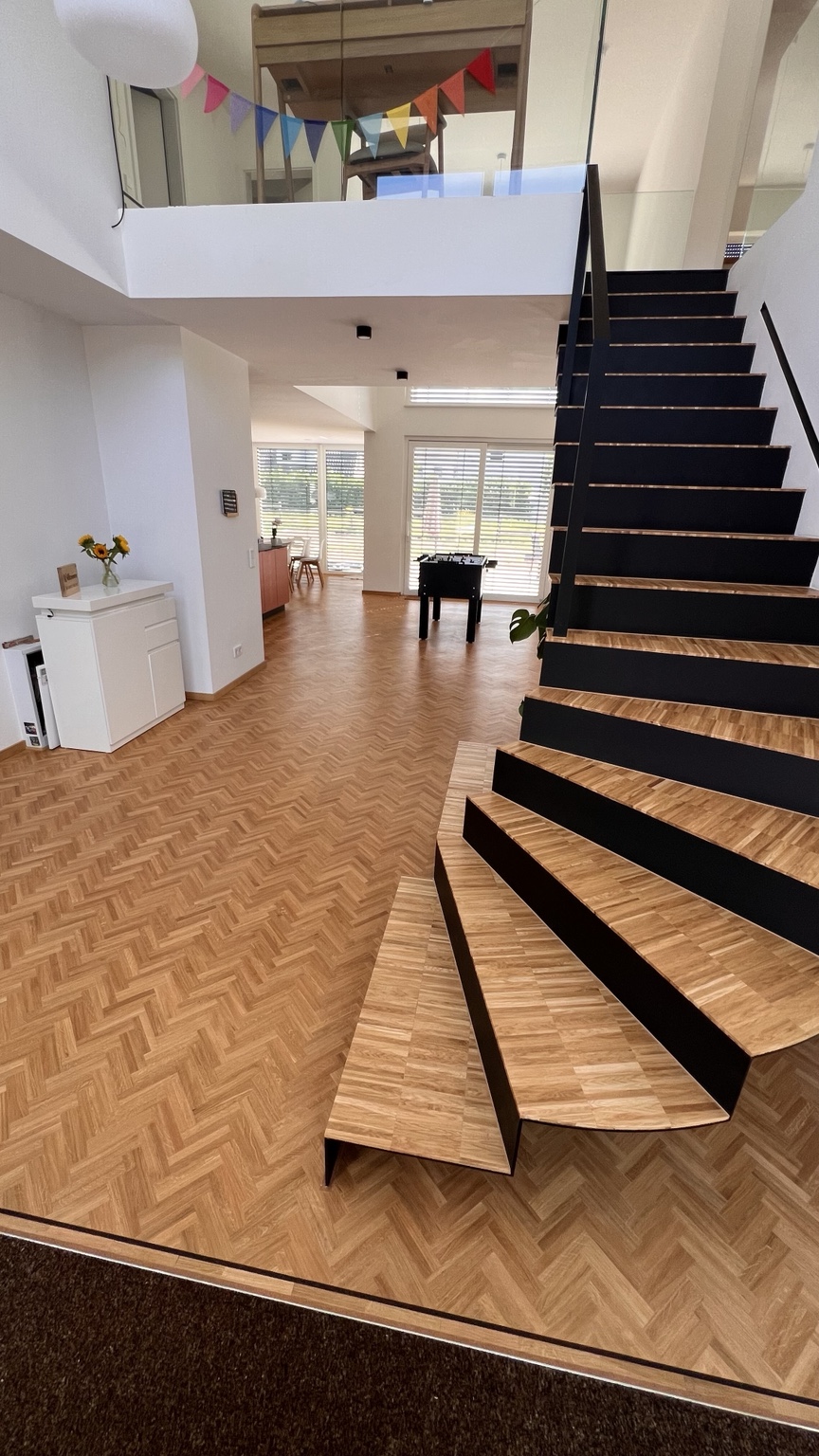 Parkettboden mit passender Holztreppe und schwarzer Treppenkonstruktion