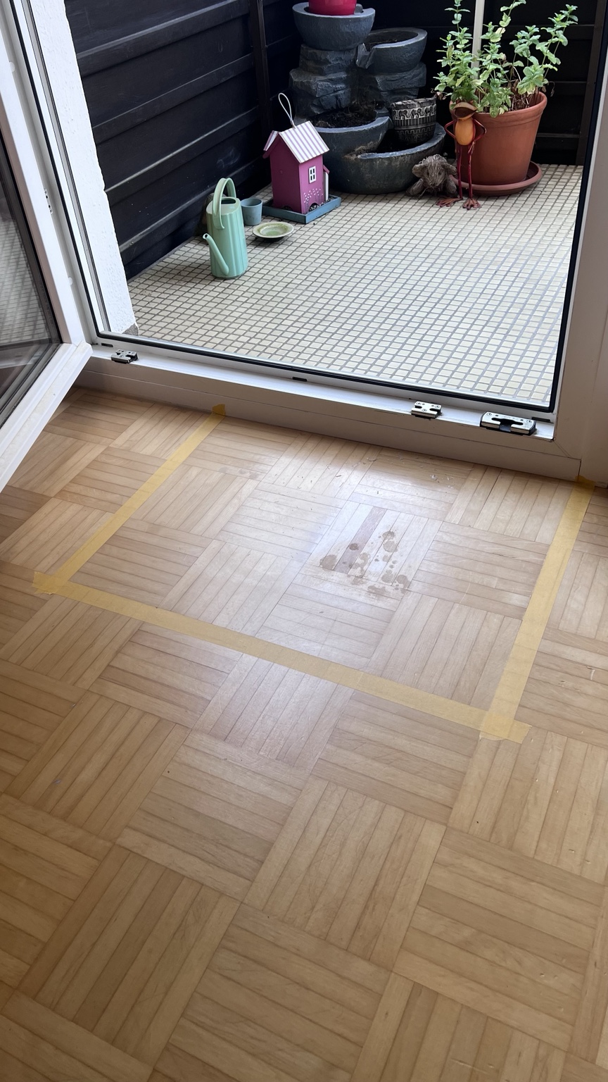 Markierte Schadstelle im Parkett vor einer Balkontür
