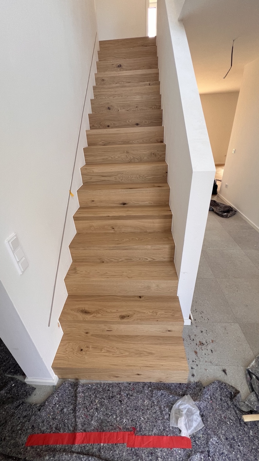 Gerade Treppe mit Eichenholzbekleidung zwischen weißen Wänden