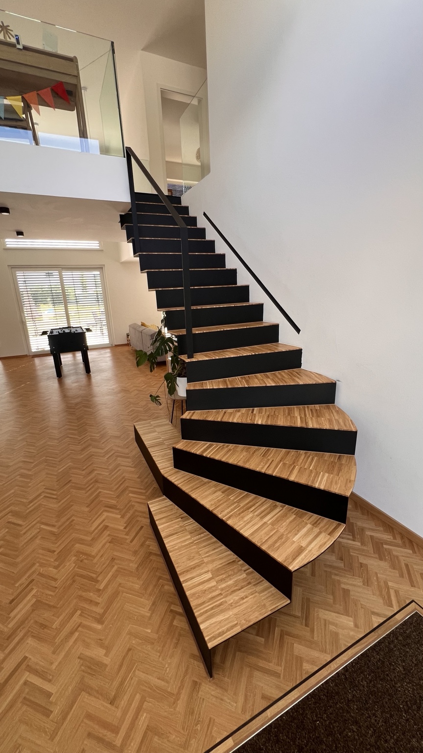 Geschwungene Treppe mit Holzstufen und schwarzer Konstruktion